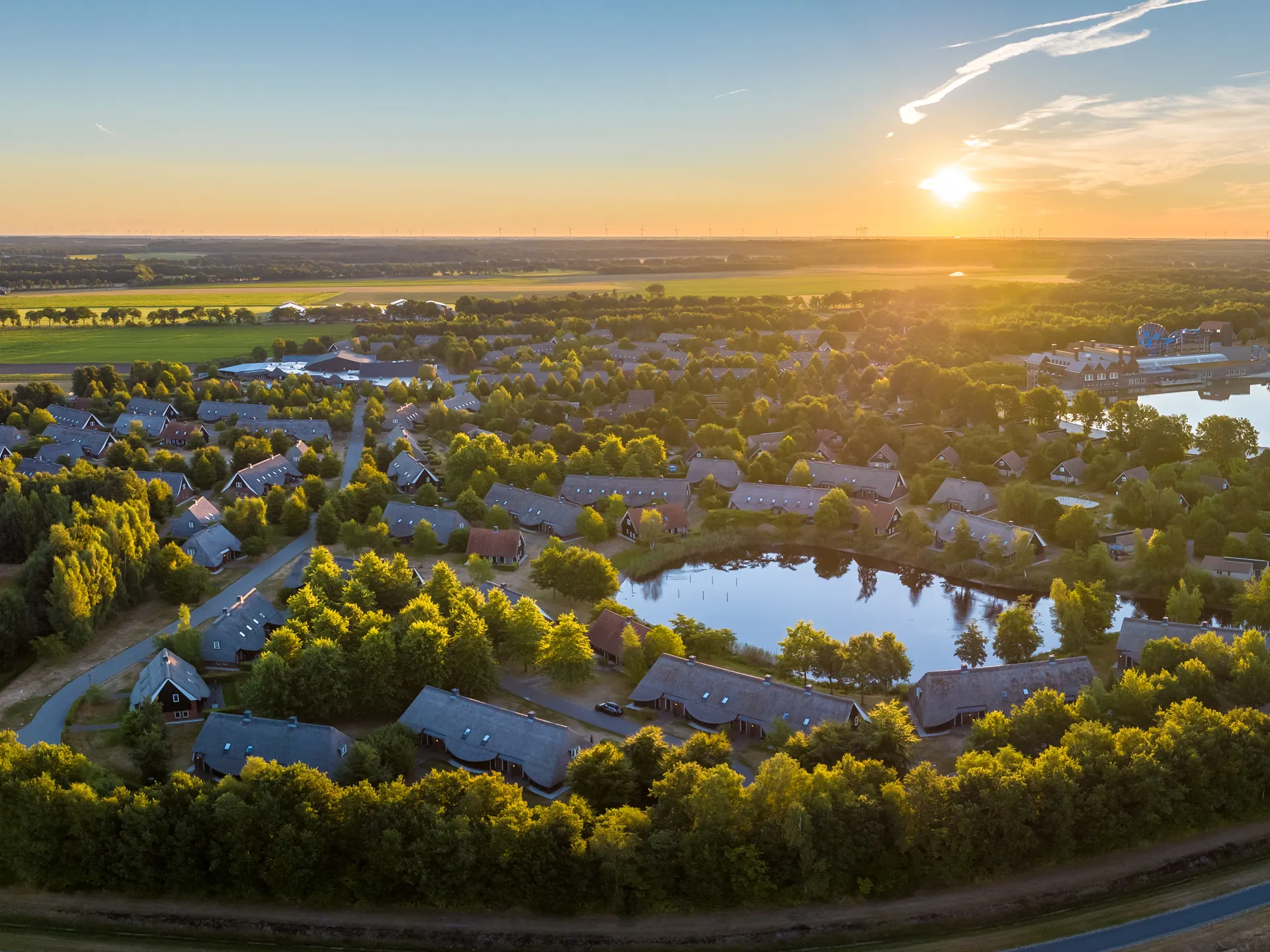 Panoramisch dronebeeld van vakantiepark Landal Hof van Saksen bij een sfeervolle zonsopkomst.