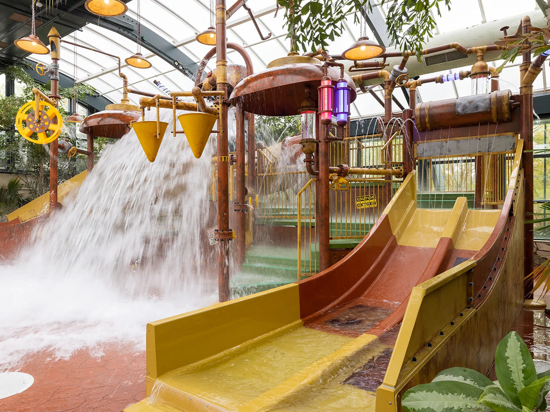 Indoor waterspeeltuin met glijbanen en omkiepende emmers bij Center Parcs Het Meerdal.